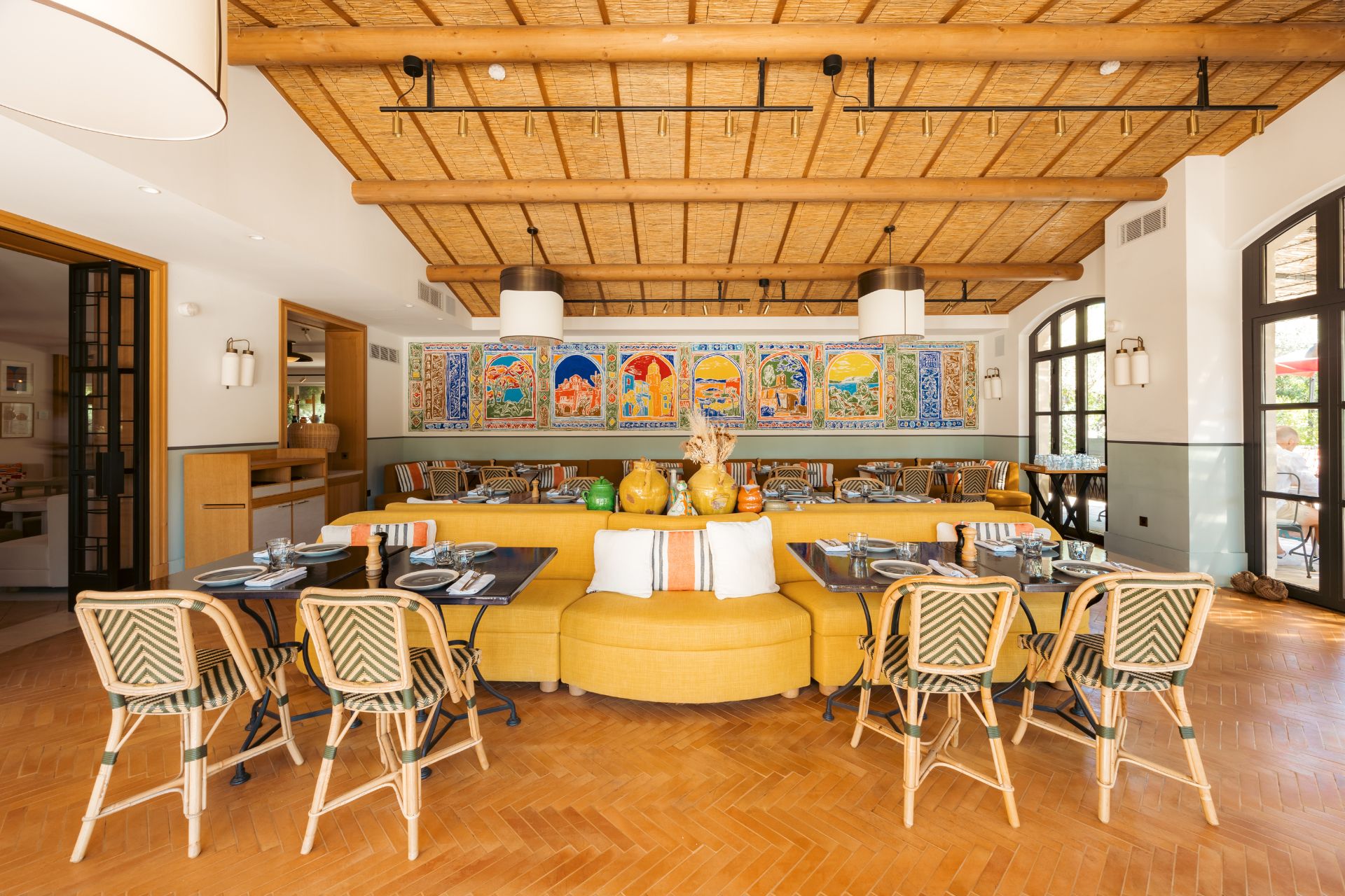 Colourful restaurant with yellow banquette seating and a blue and yellow wall mural