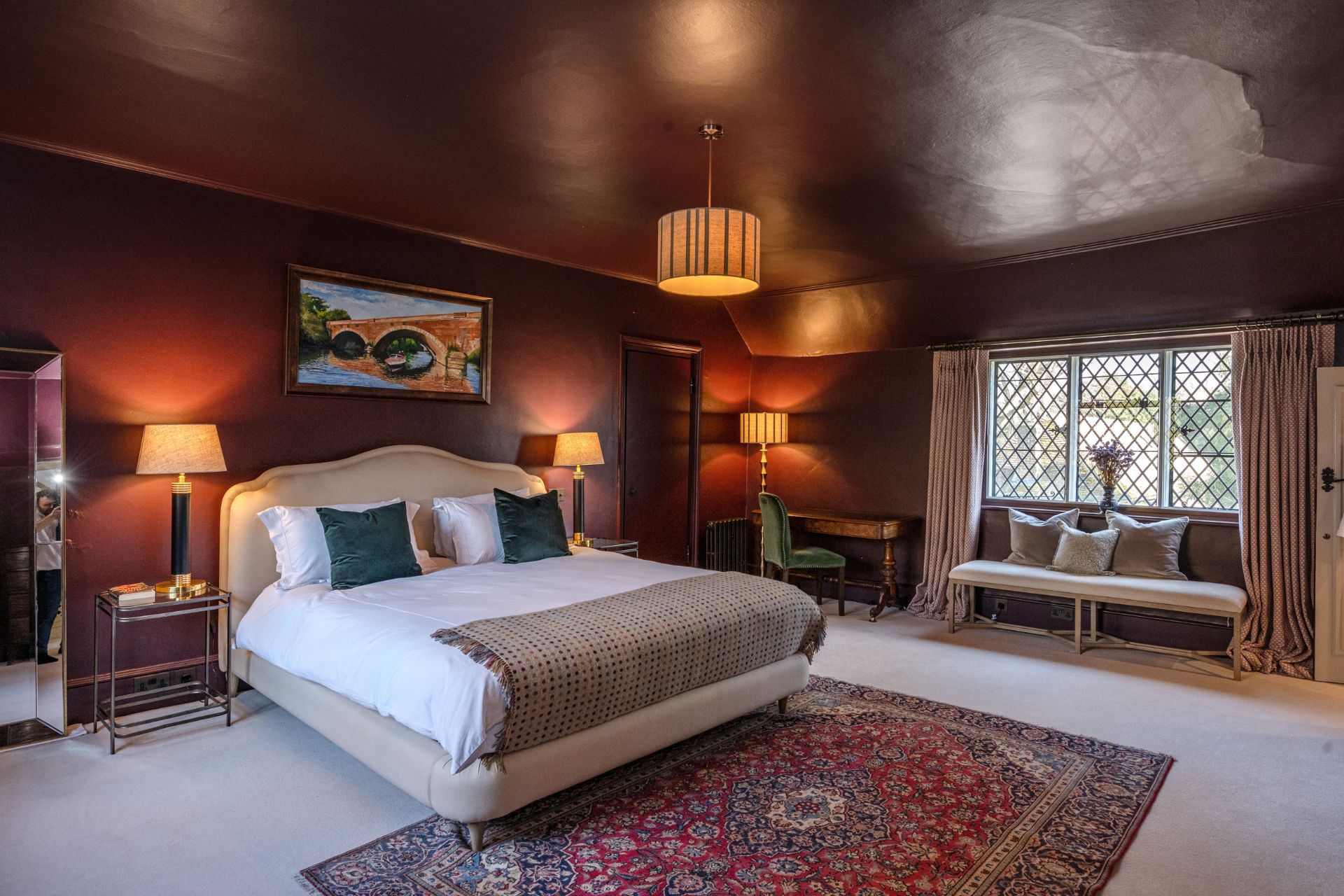 Bdroom with colour-drenched burgundy walls, a cream bed and leaded windows