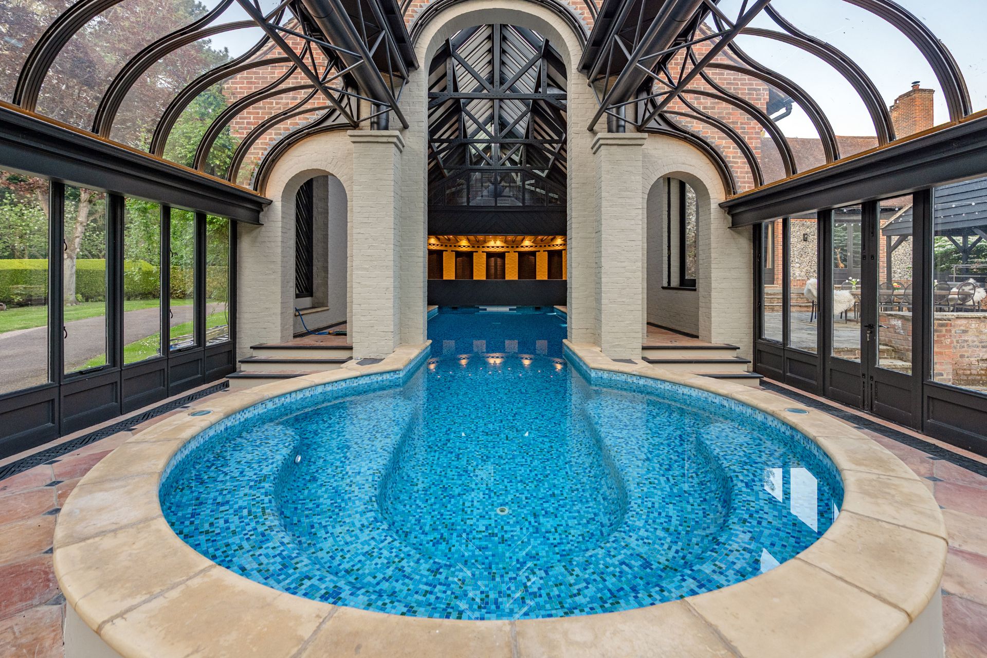 Jacuzzi and swimming pool housed in a glass pavilion