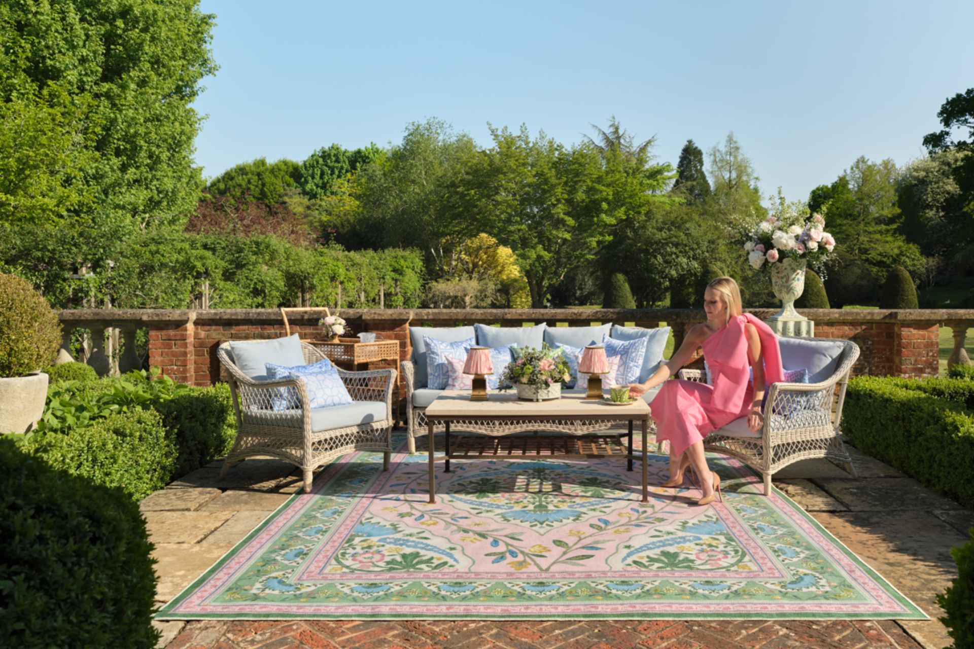 Outdoor dining area with pink and green floral rug and pale blue cushions