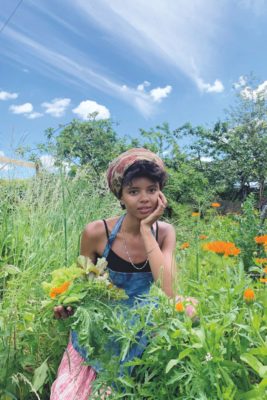 Poppy Okotcha sitting in a wildflower meadow