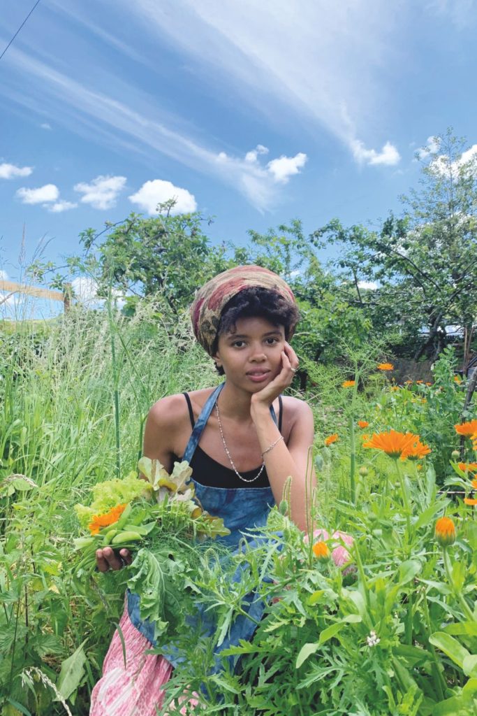Poppy Okotcha sitting in a wildflower meadow