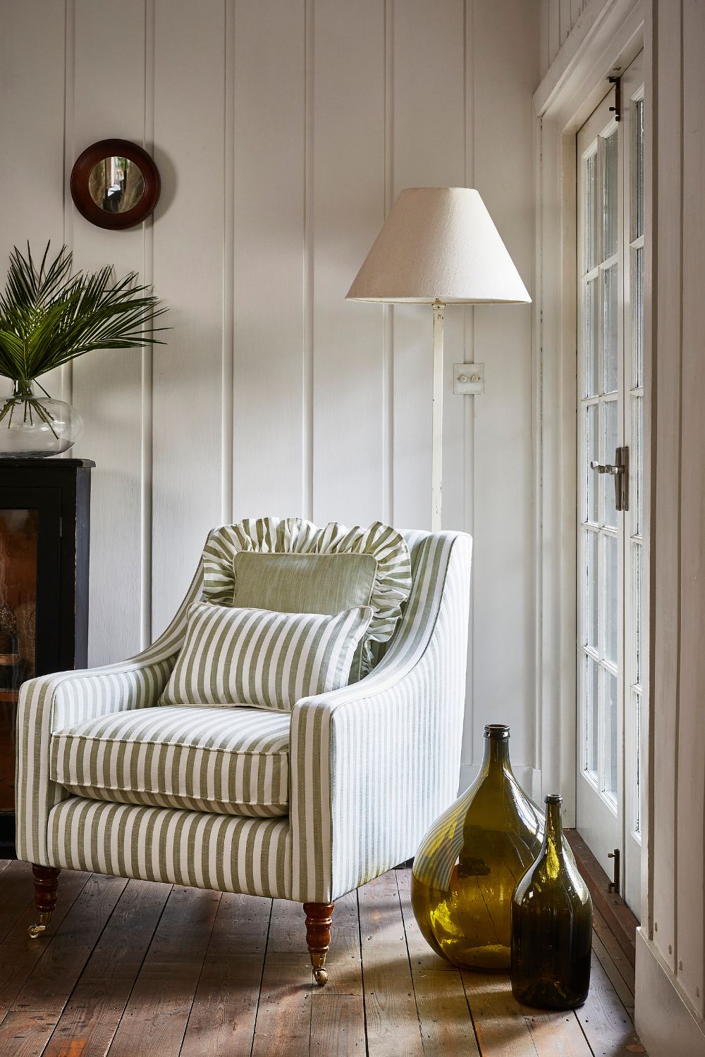 Living area with white and green striped armchair and white floor lamp