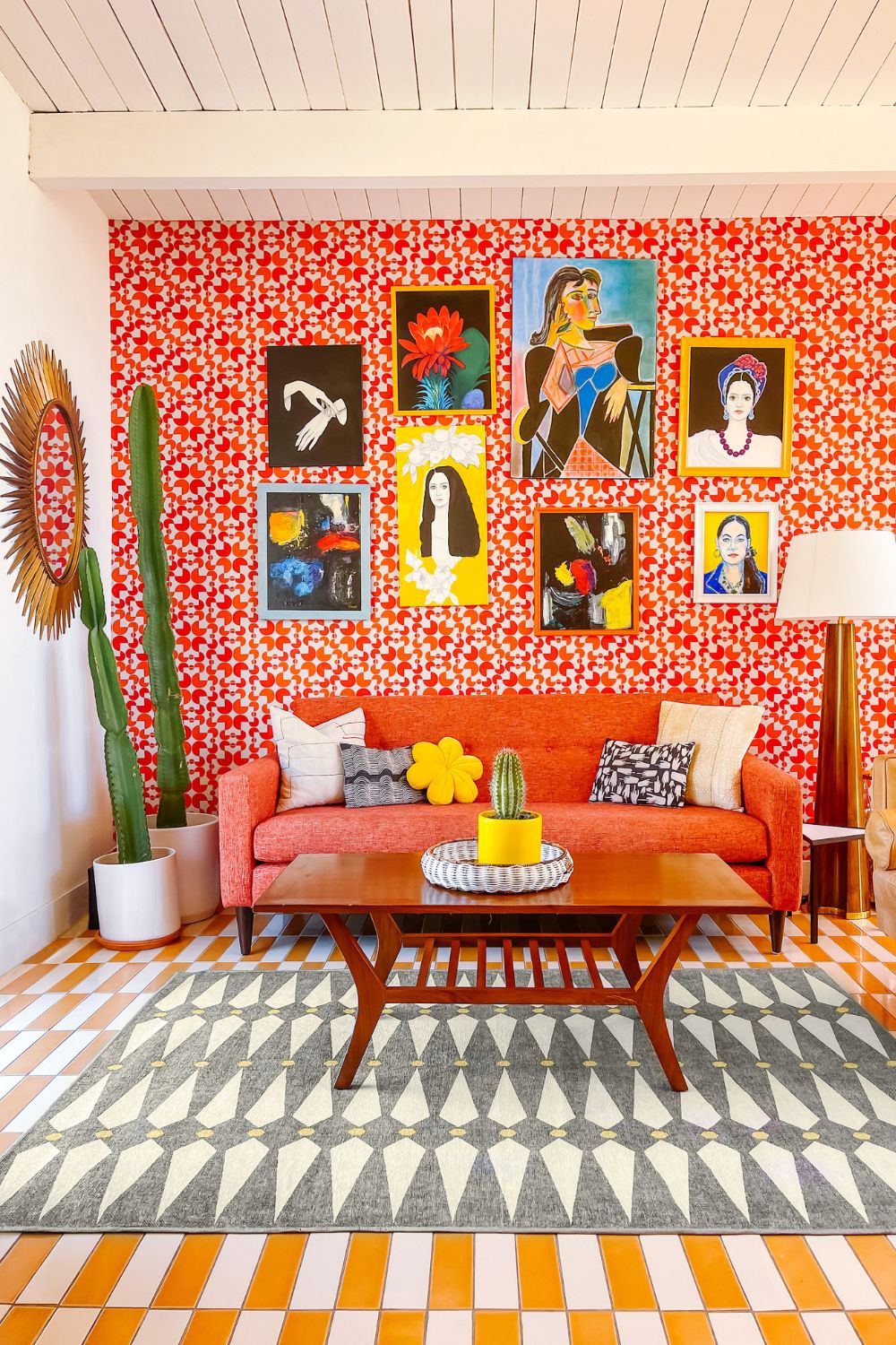 Living room with red and white geometric wallpaper, a red sofa, and blue, yellow and white patterned rugs