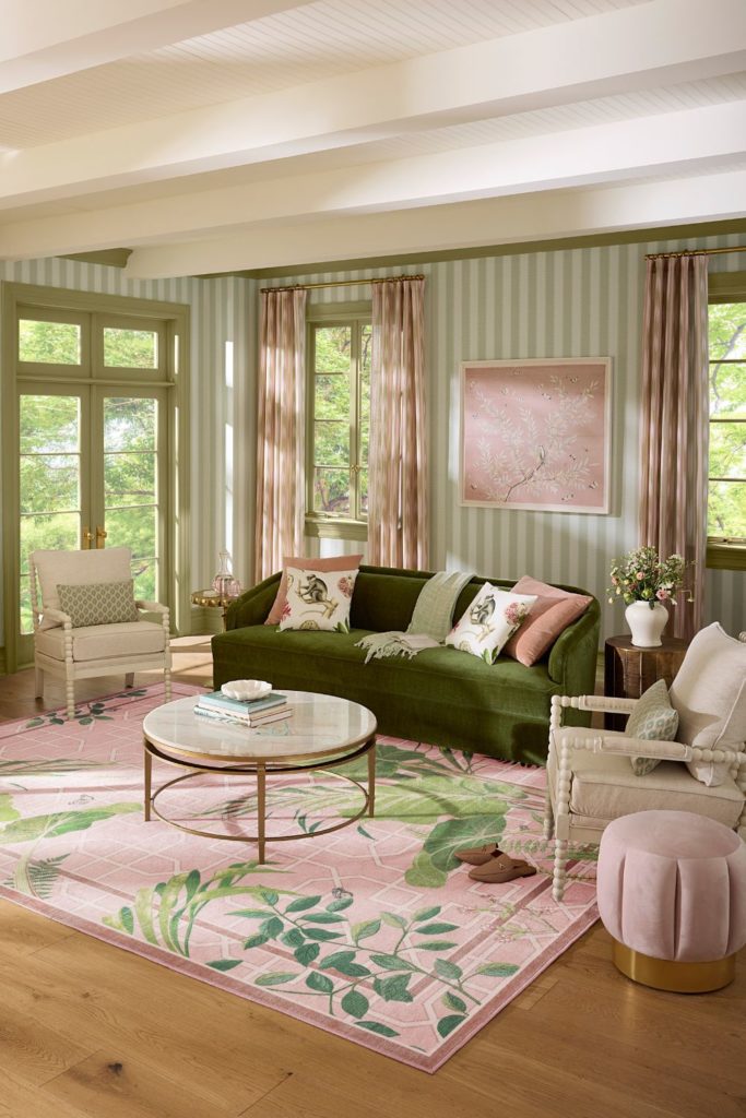 Living room with olive green velvet sofa, pink rug, and pink cushions