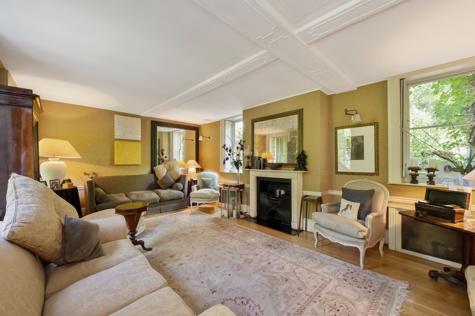 Living room with musyard yellow walls, cream carpets and a marble fireplace