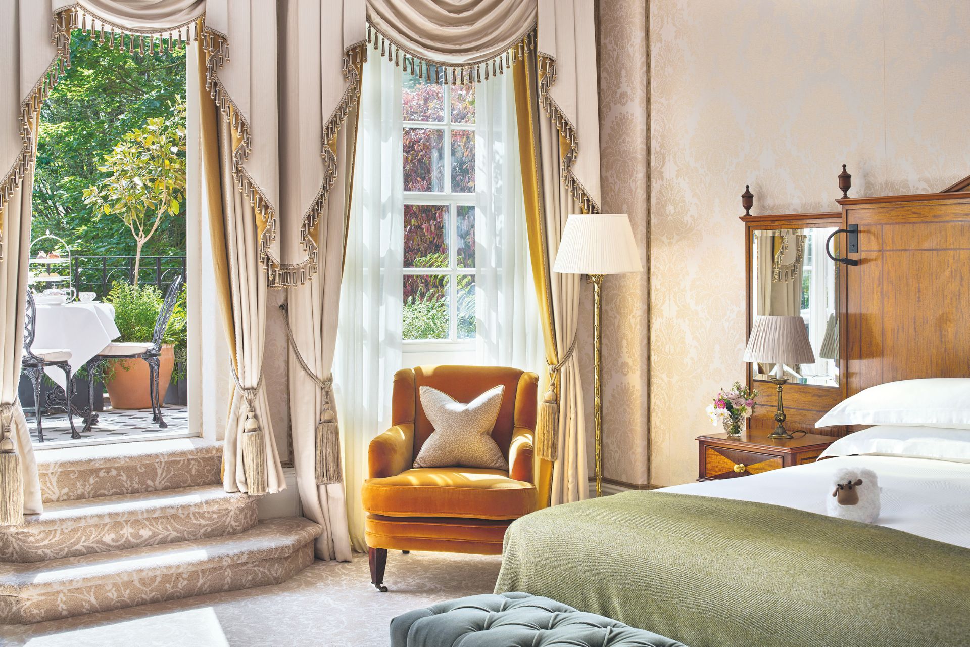 Hotel room with cream silk drapes, a green bedspread, and a large terrace