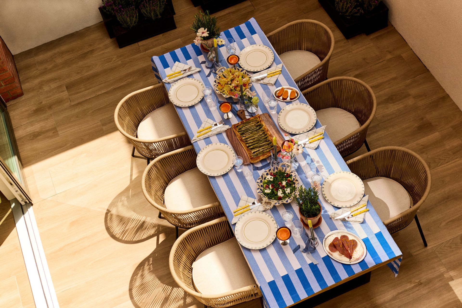 Aerial view of wooden dining table dressed with a blue and white striped tablecloth
