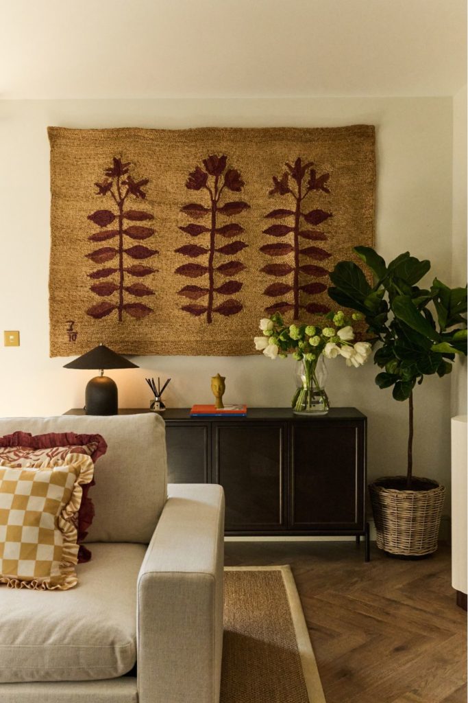 Living room with qall tapestry and grey sofa with yellow gingham cushions