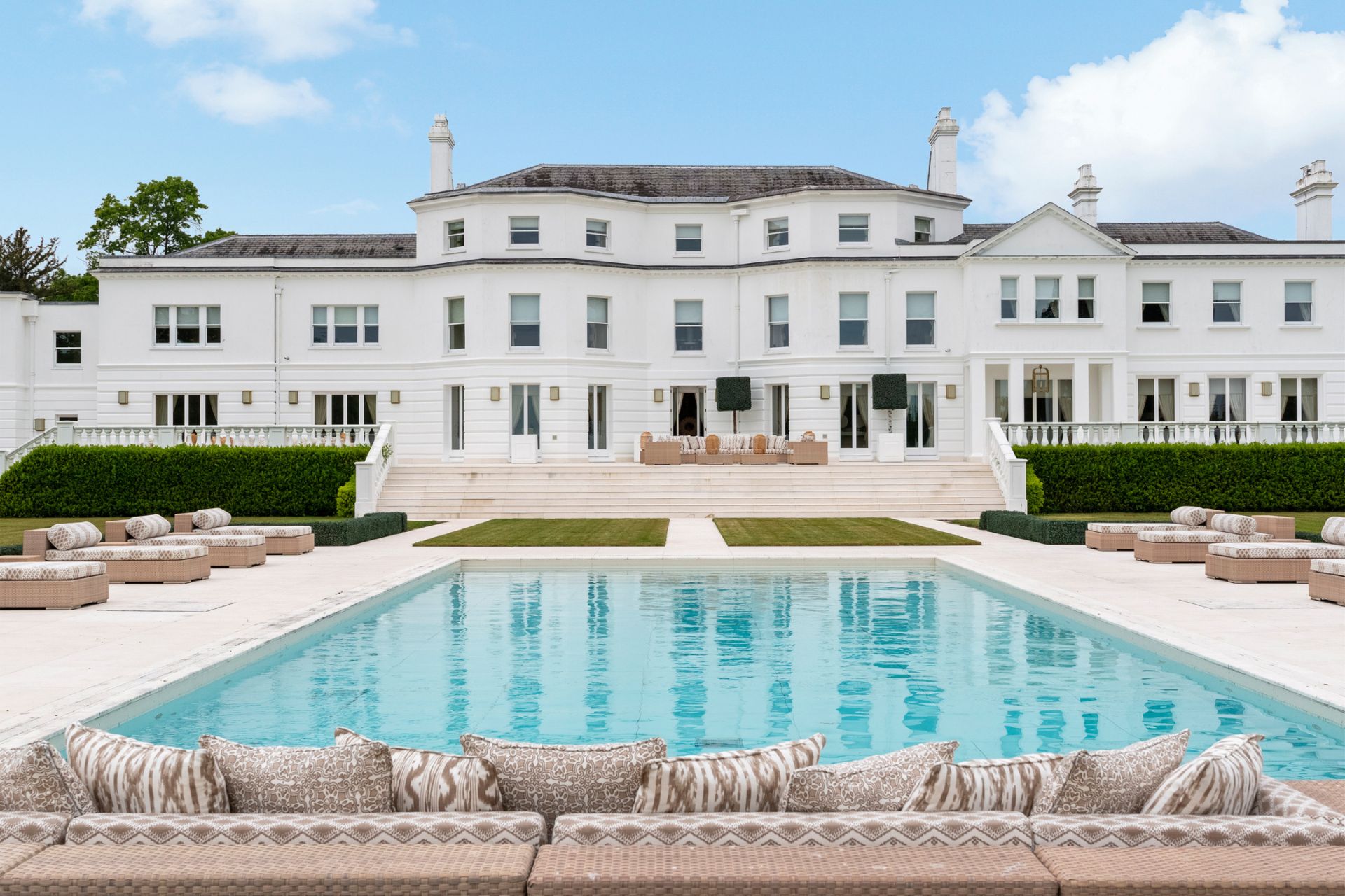 Rear view of white stucco mansion with outdoor pool