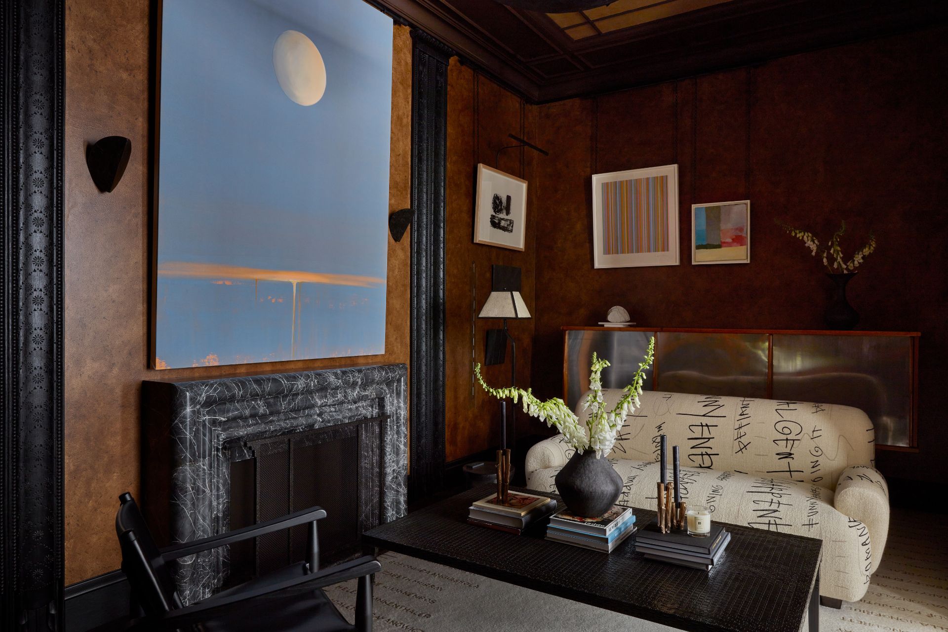 Living room with deep brown textured walls, a pale blue accent wall with a grey marble fireplace, and a cream sofa with black sbtract patterns