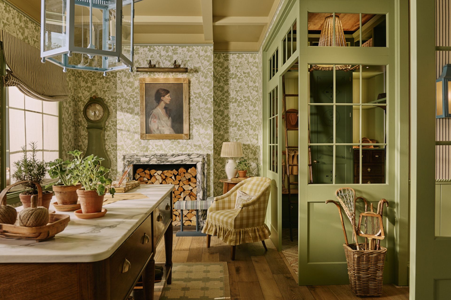Boot room with sage green wood panelling, floral wallpaper, a yellow gingham armchair, and a central wooden island with a white marble worktop