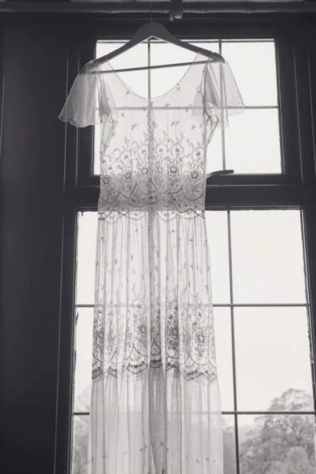 Lace dress hanging by window, listed on Abigail’s Vintage Bridal