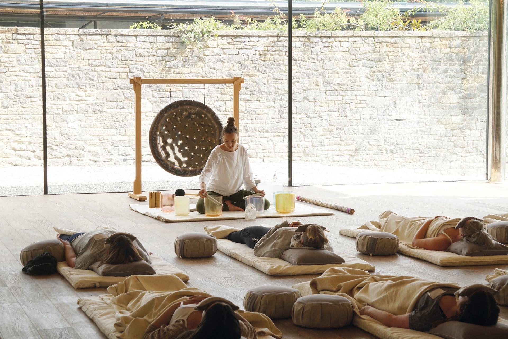 A sound bath practitioner with people meditating