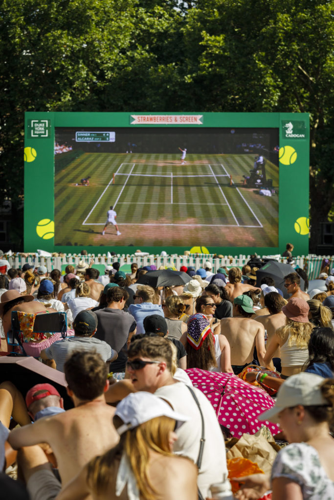 A view through a crowd of people watching Wimbledon on a big screen in Chelsea, London