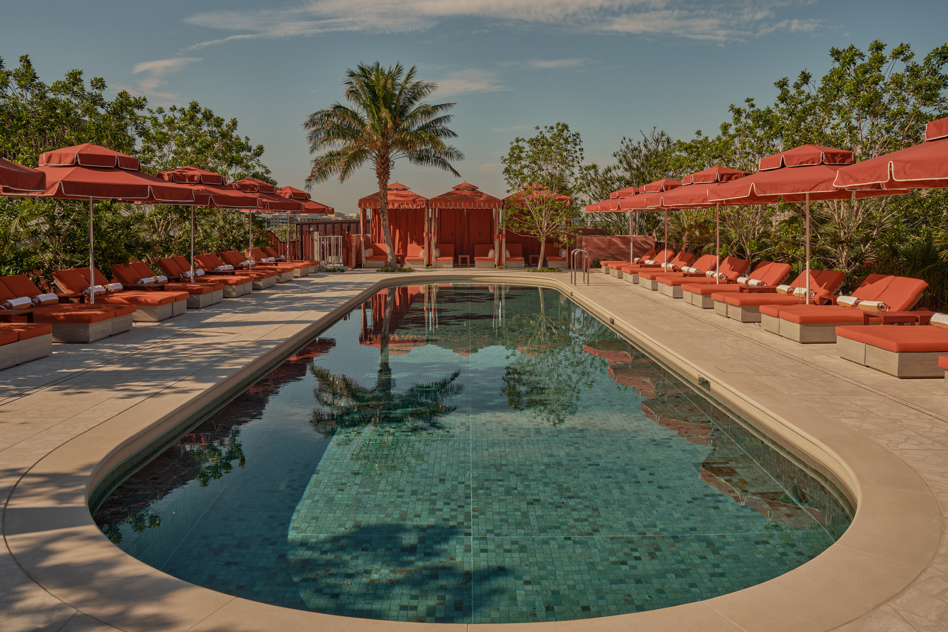 A swimming pool flanked by red loungers