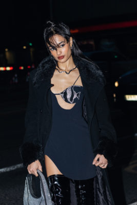 Woman with half up half down hairstyle wearing black dress and coat