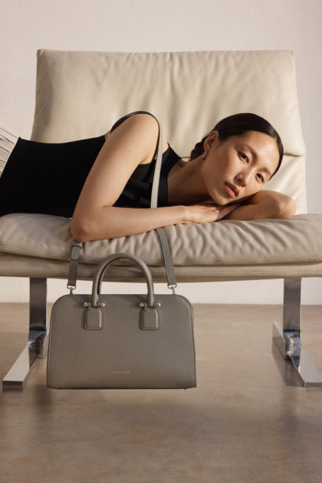Woman lying across chair with handbag