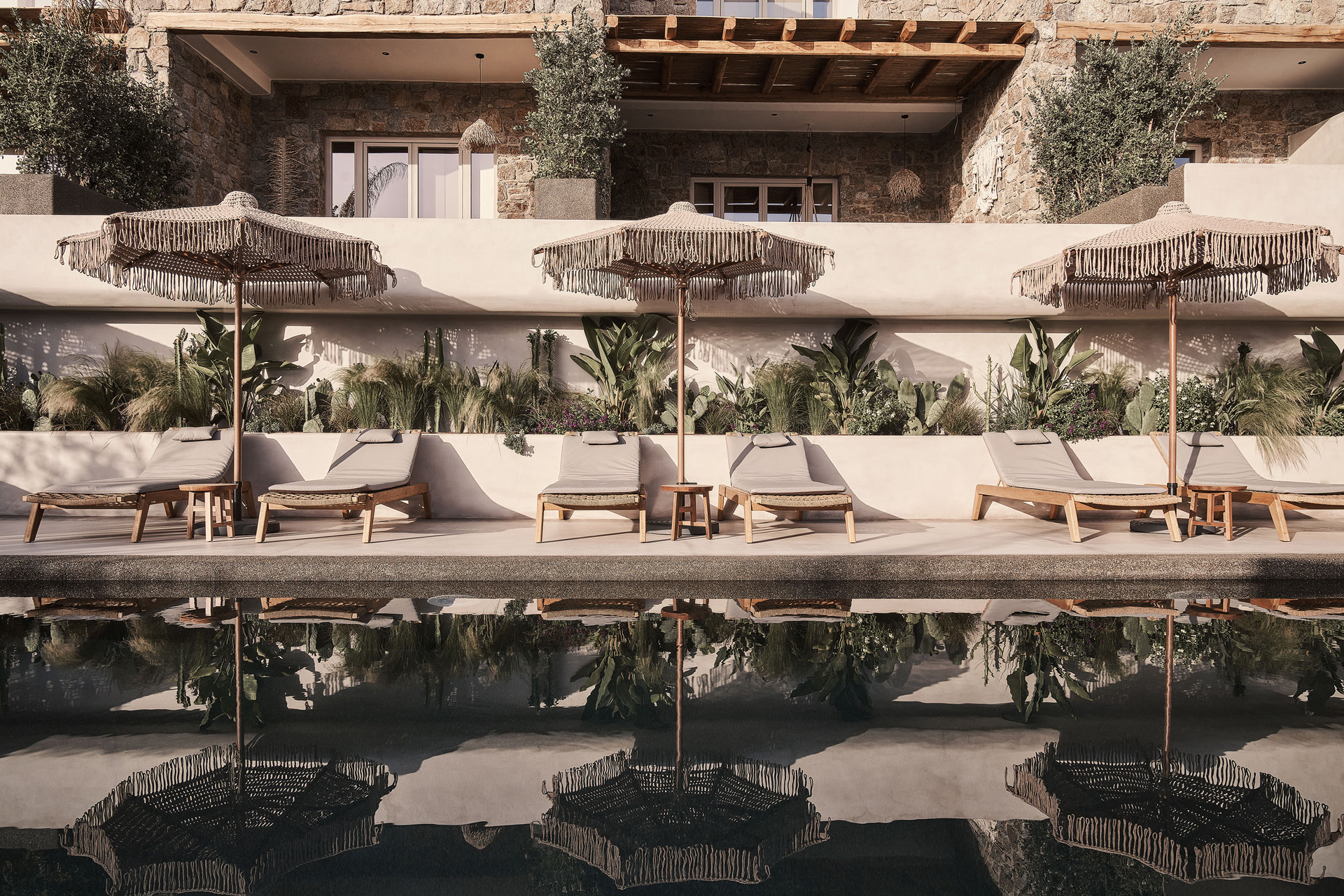Small tables flank the pool at Amyth of Mykonos Agios Stefanos.