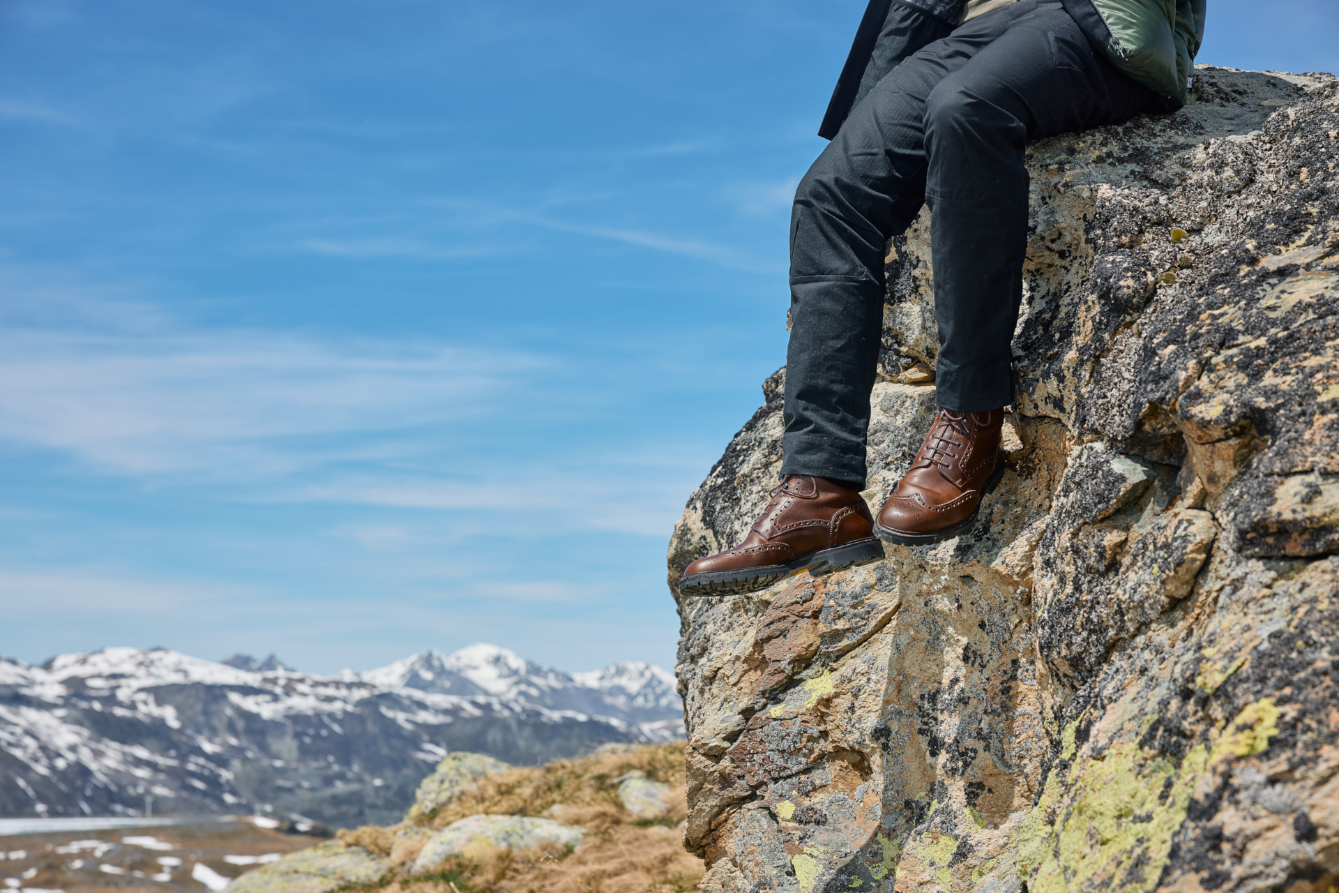 Close up of man sat on rock with boots visible