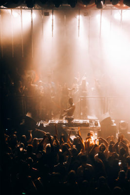 A DJ performs to a crowd in a packed club