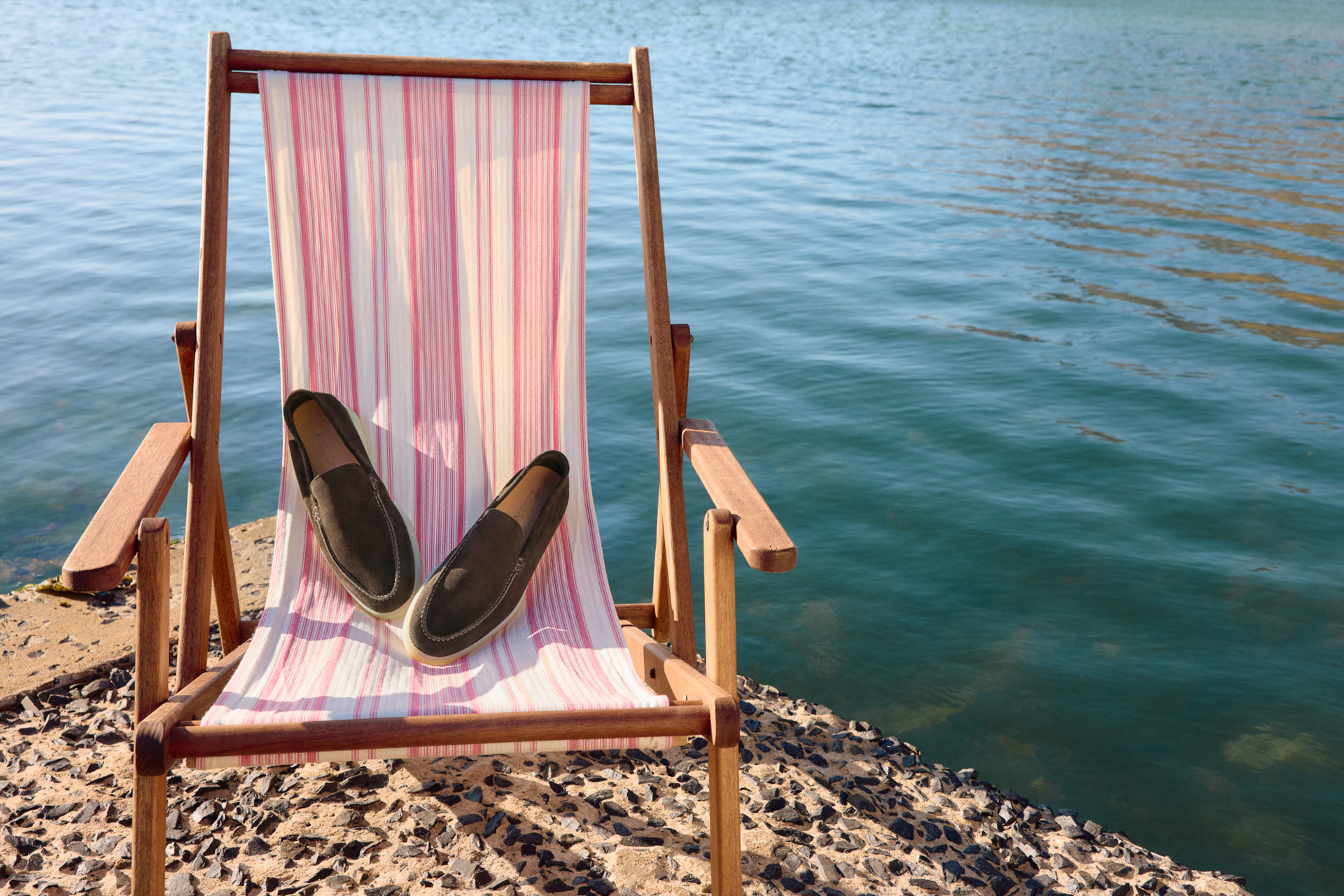 Loafers on deck chair by water
