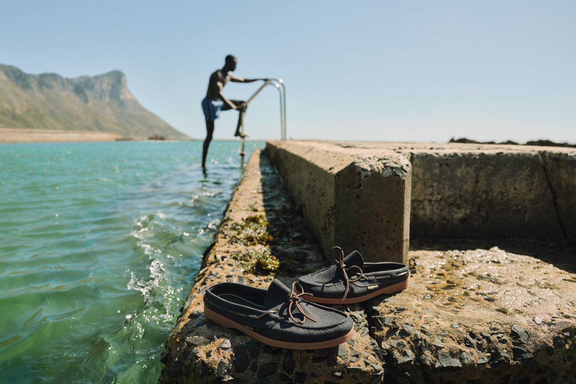 Man stepping out water with shoes in the foreground 