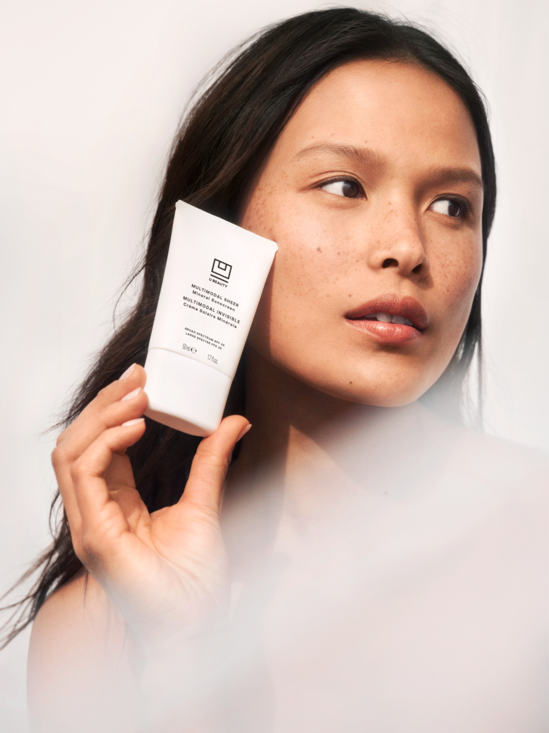 Model holding skincare product up to her face