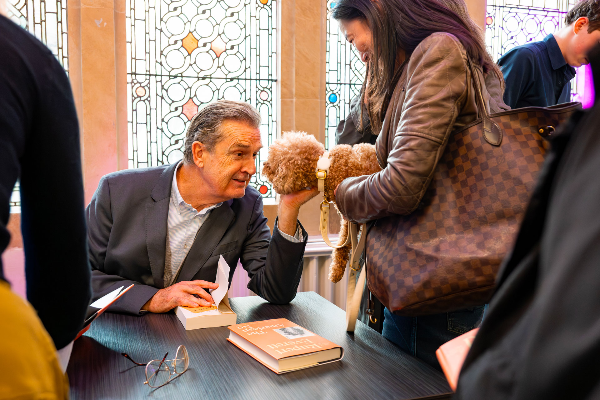 Rupert Everett at the Chelsea Arts Festival book signing, stroking a dog