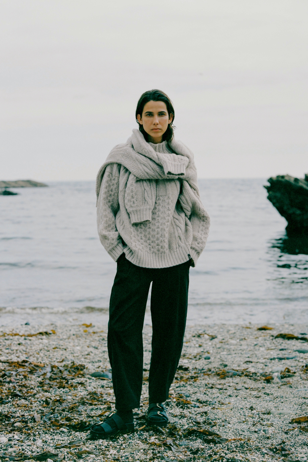 Woman in grey knitted jumper and black trousers