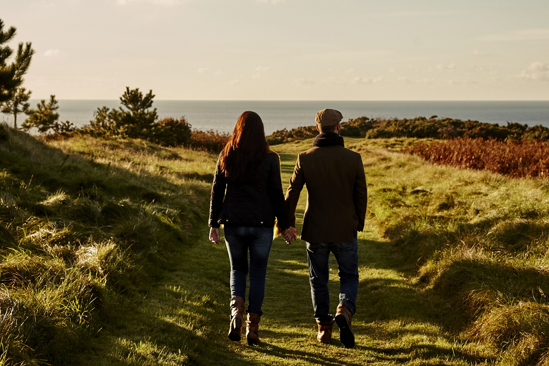 A couple walking in a field by the sea