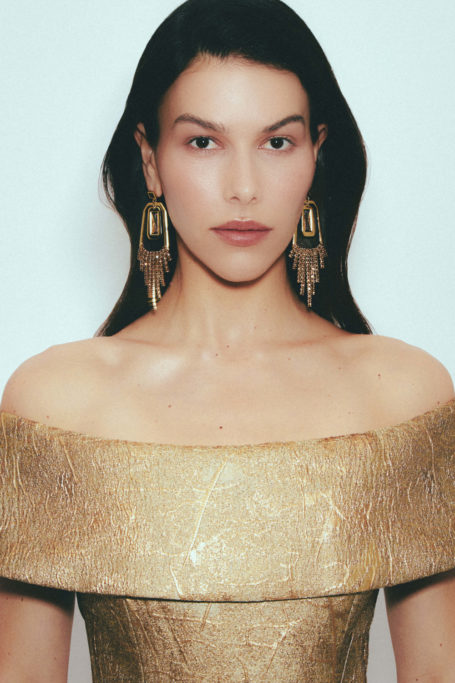 Woman wearing gold top and earrings