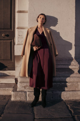Woman leaning against wall at sunset