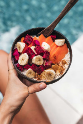 Woman holding a healthy breakfast bowl by a pool