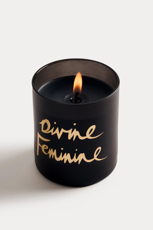 A black candle with the words 'divine feminine'