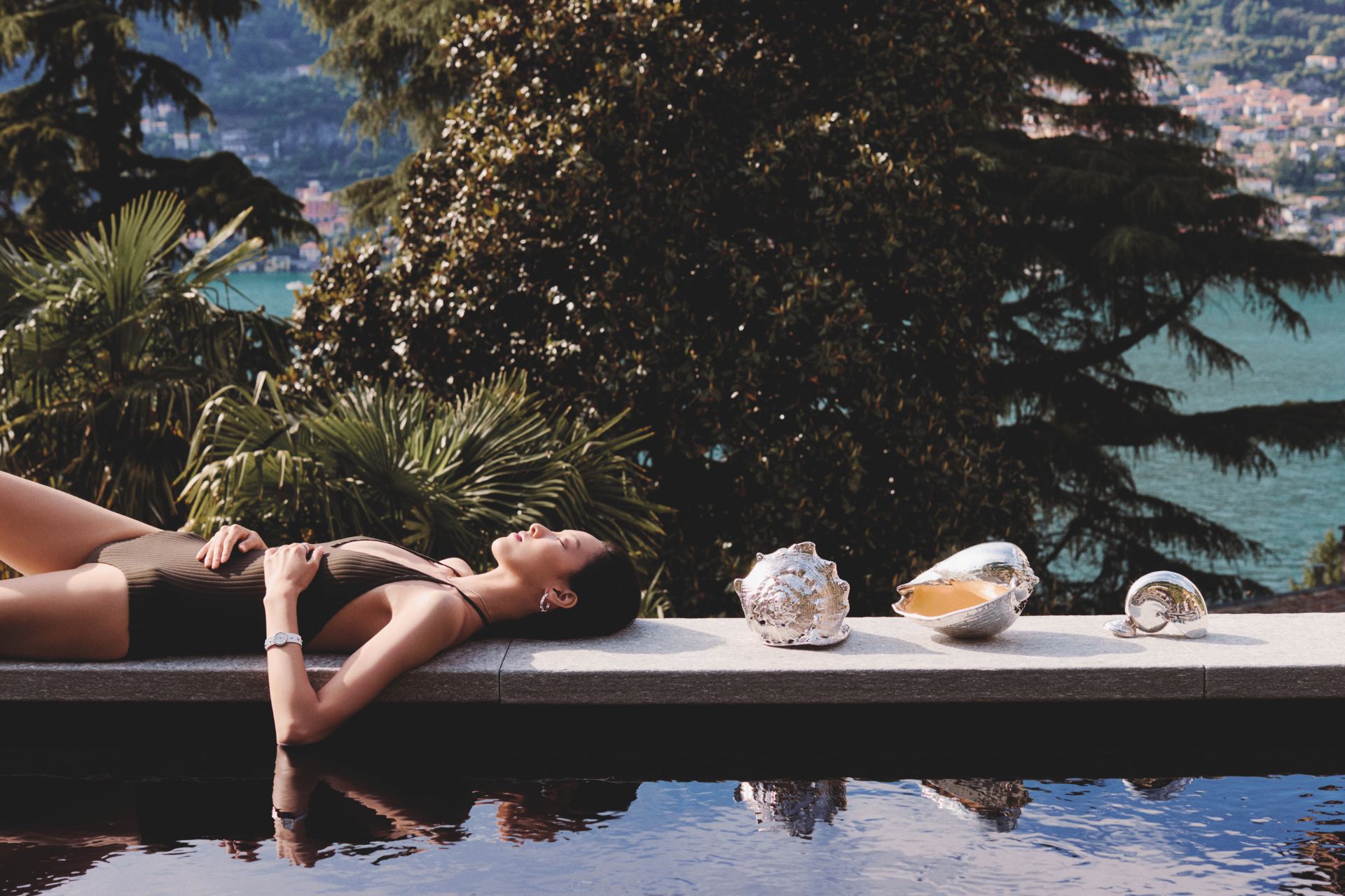 Model lies by pool with Buccellati silver shells