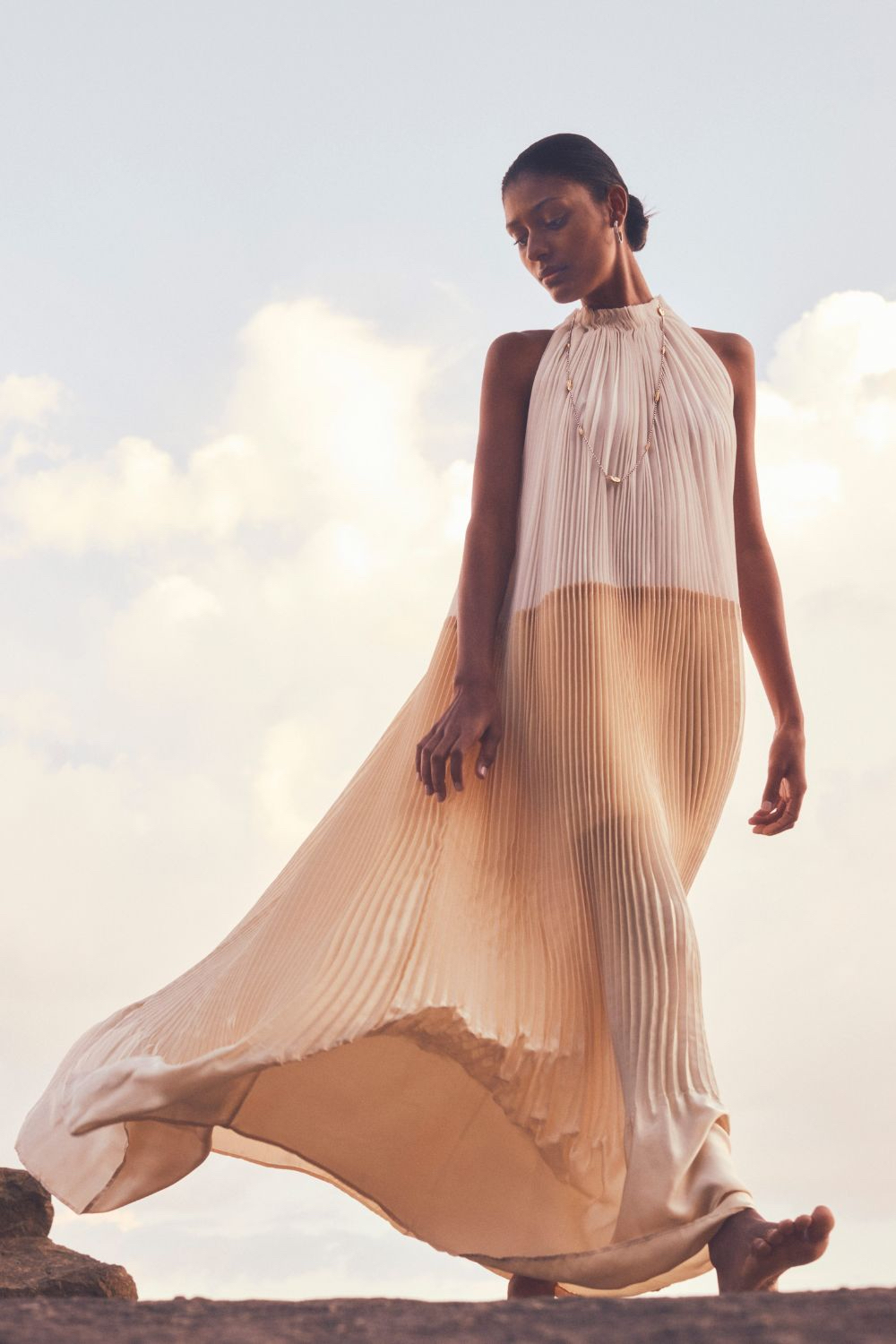Model in flowing dress and Buccellati jewellery walking barefoot by pool