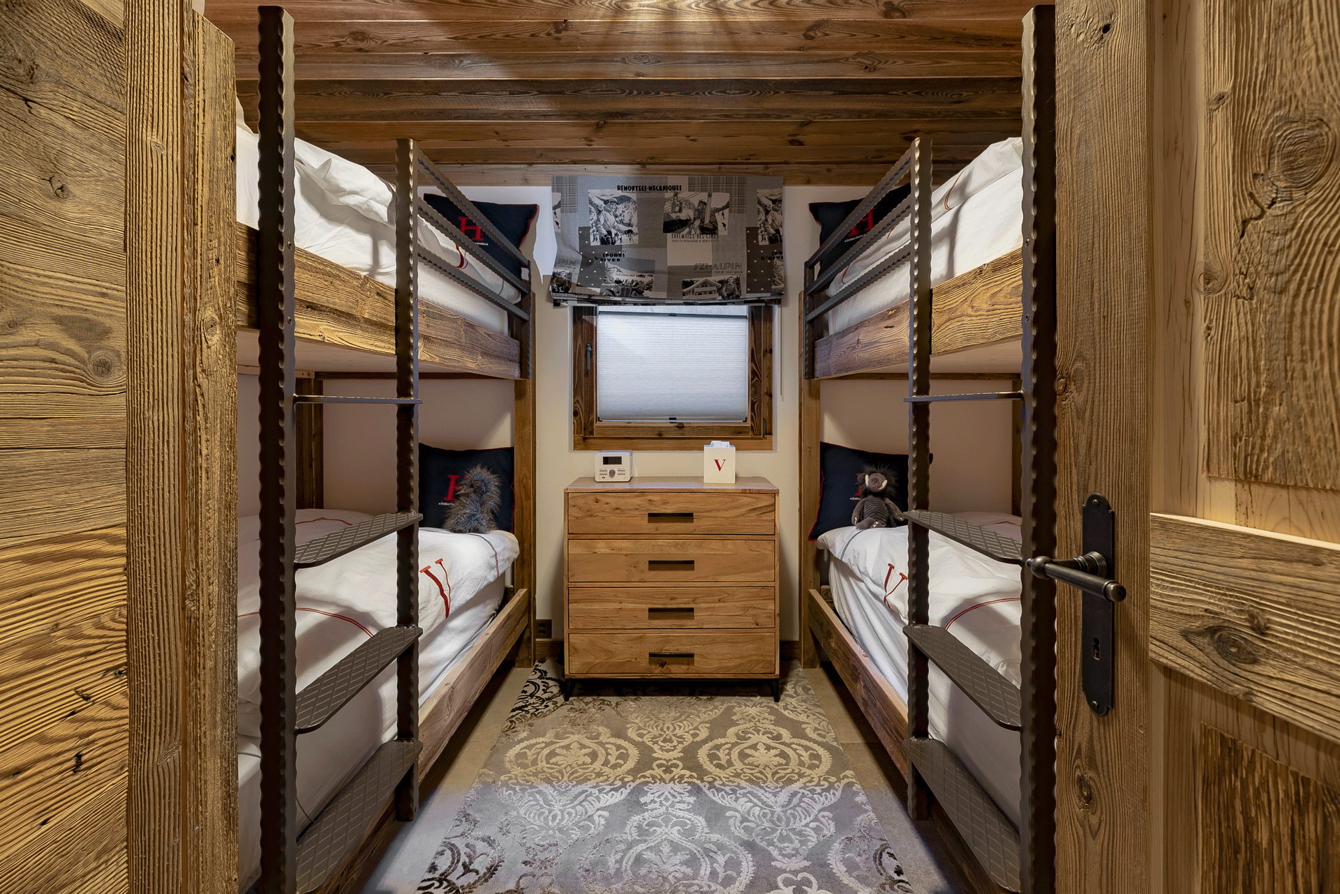 Two sets of bunk beds arranged either side of a window looking out to a snowy landscape
