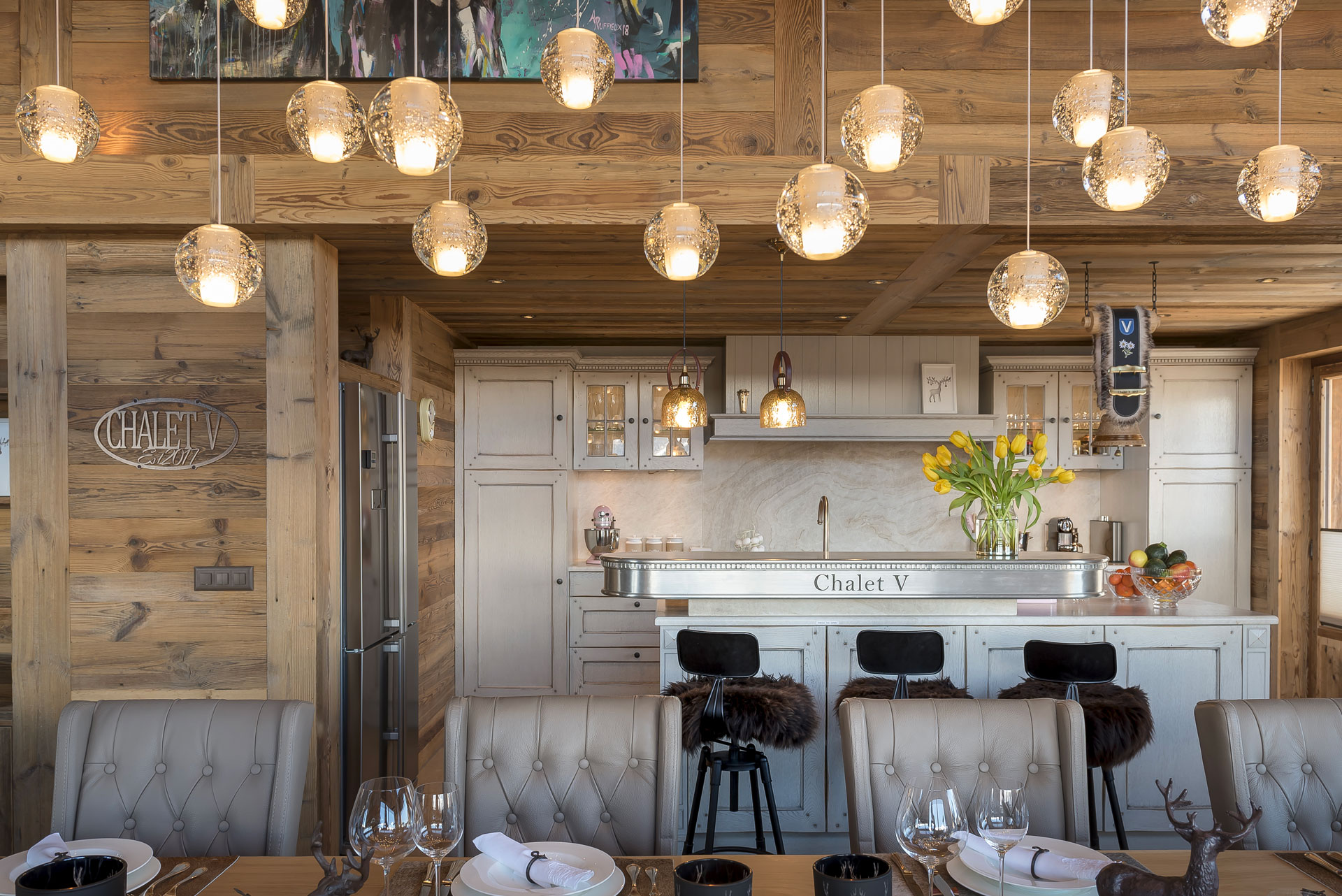A kitchen in a chalet with many dangling globe lights and a metal oven-stove unit