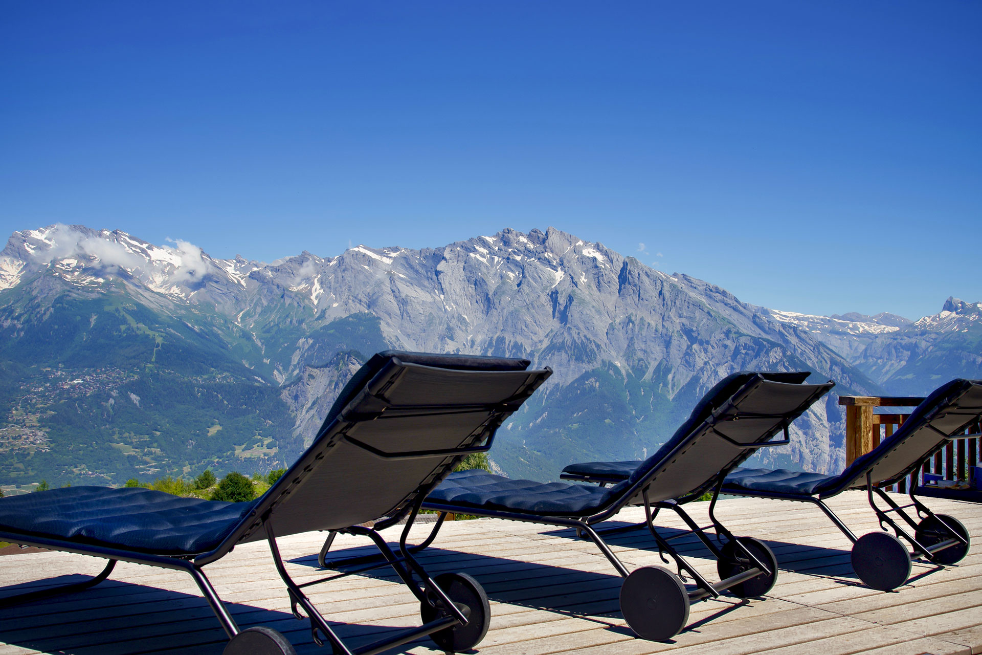 Sun-loungers on decking in front of mountains
