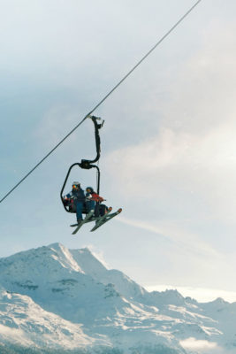 A pair of skiers are sat on a chair lift