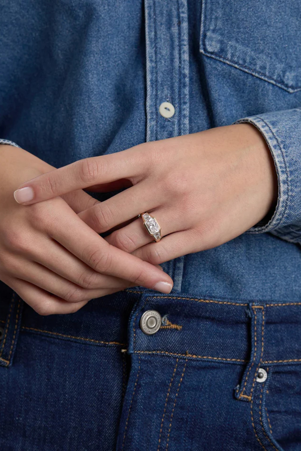 Hands clasped in front of person wearing denim