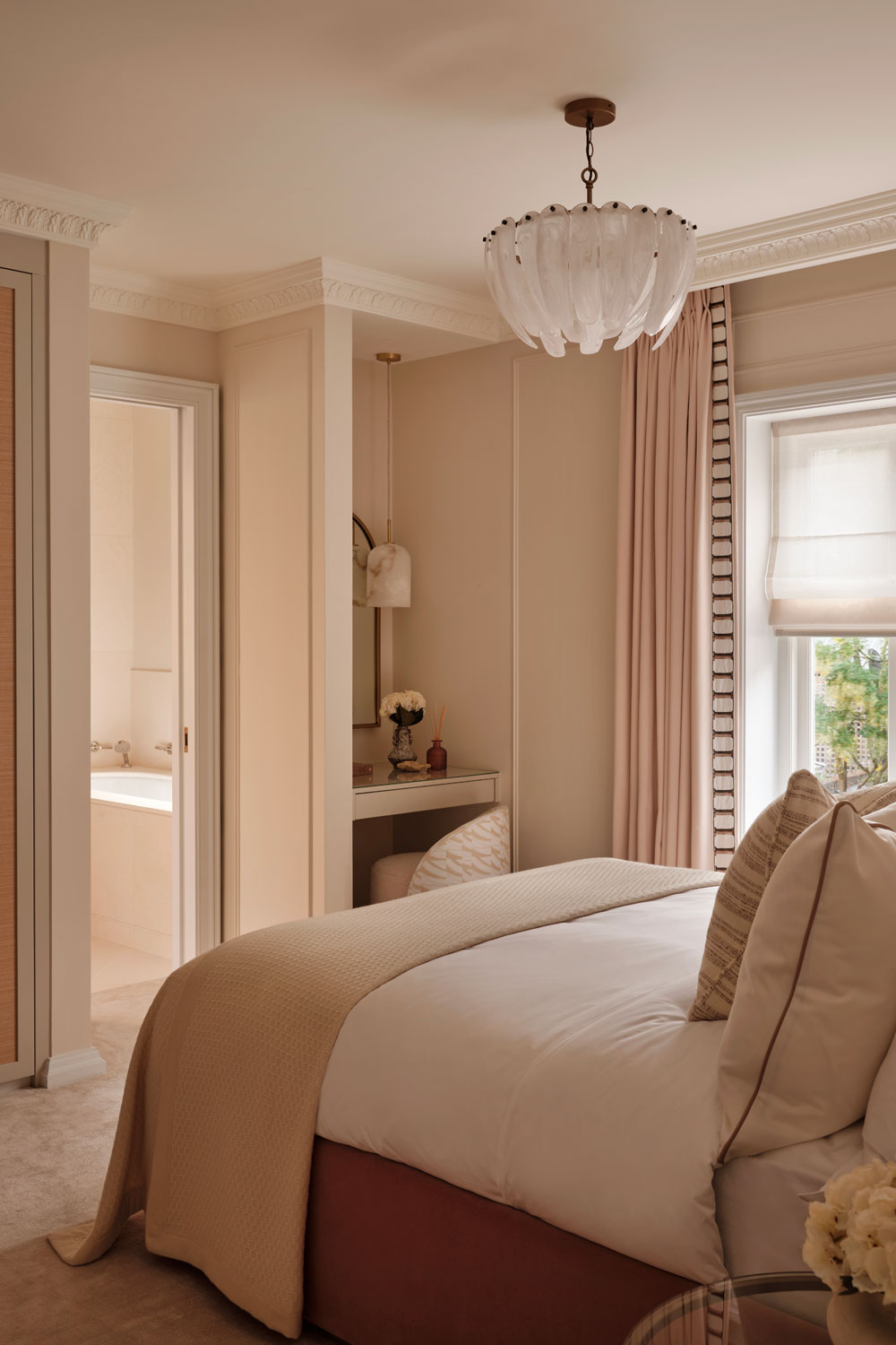 A pink bedroom with a shell chandelier and a dressing nook in the corner