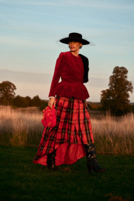 Woman on fashion shoot wearing red jacket and tartan skirt