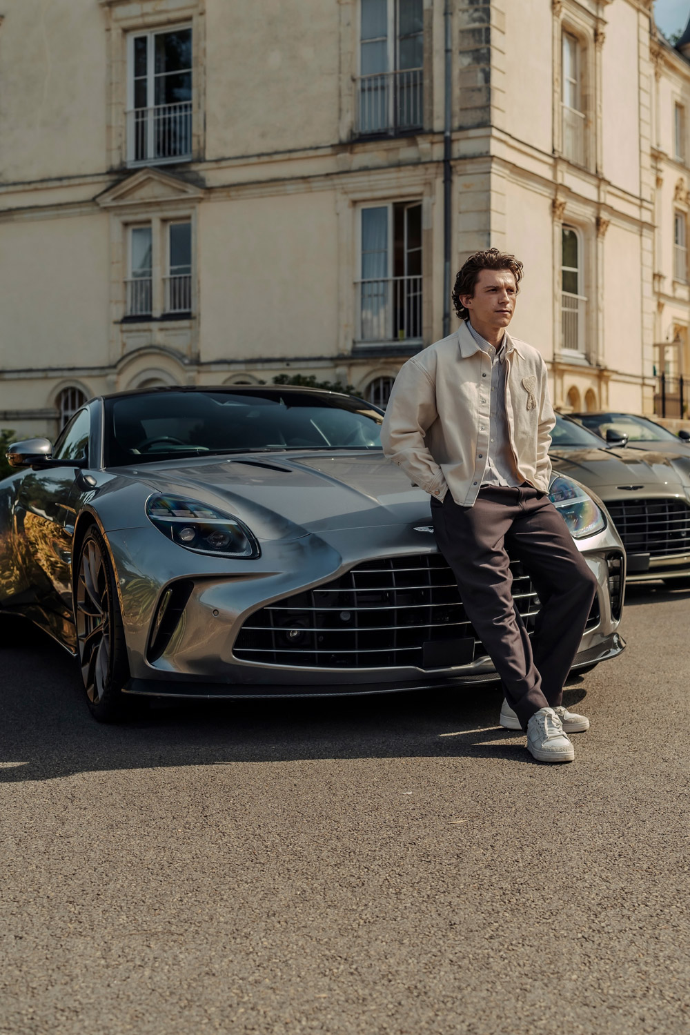 Tom Holland standing beside an Aston Martin