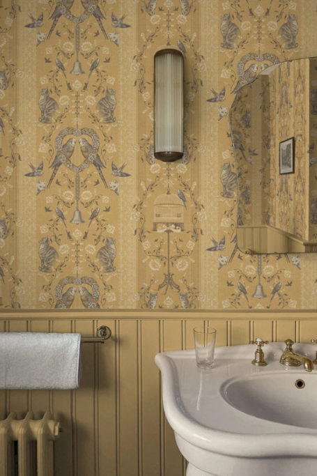 Yellow bathroom with wallpaper by British brand Divine Savages
