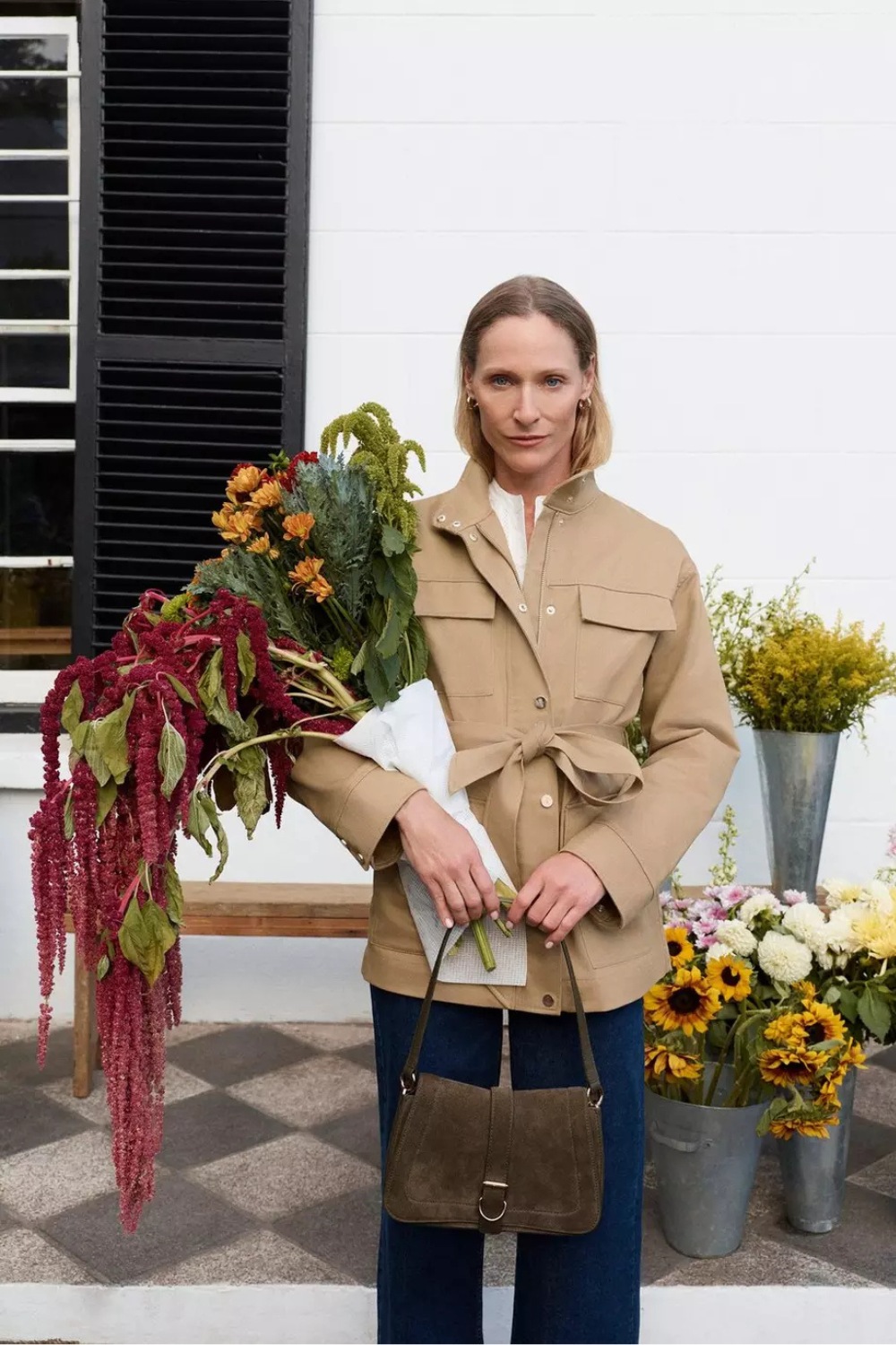 Woman wearing trench jacket and holding bouquet of flowers