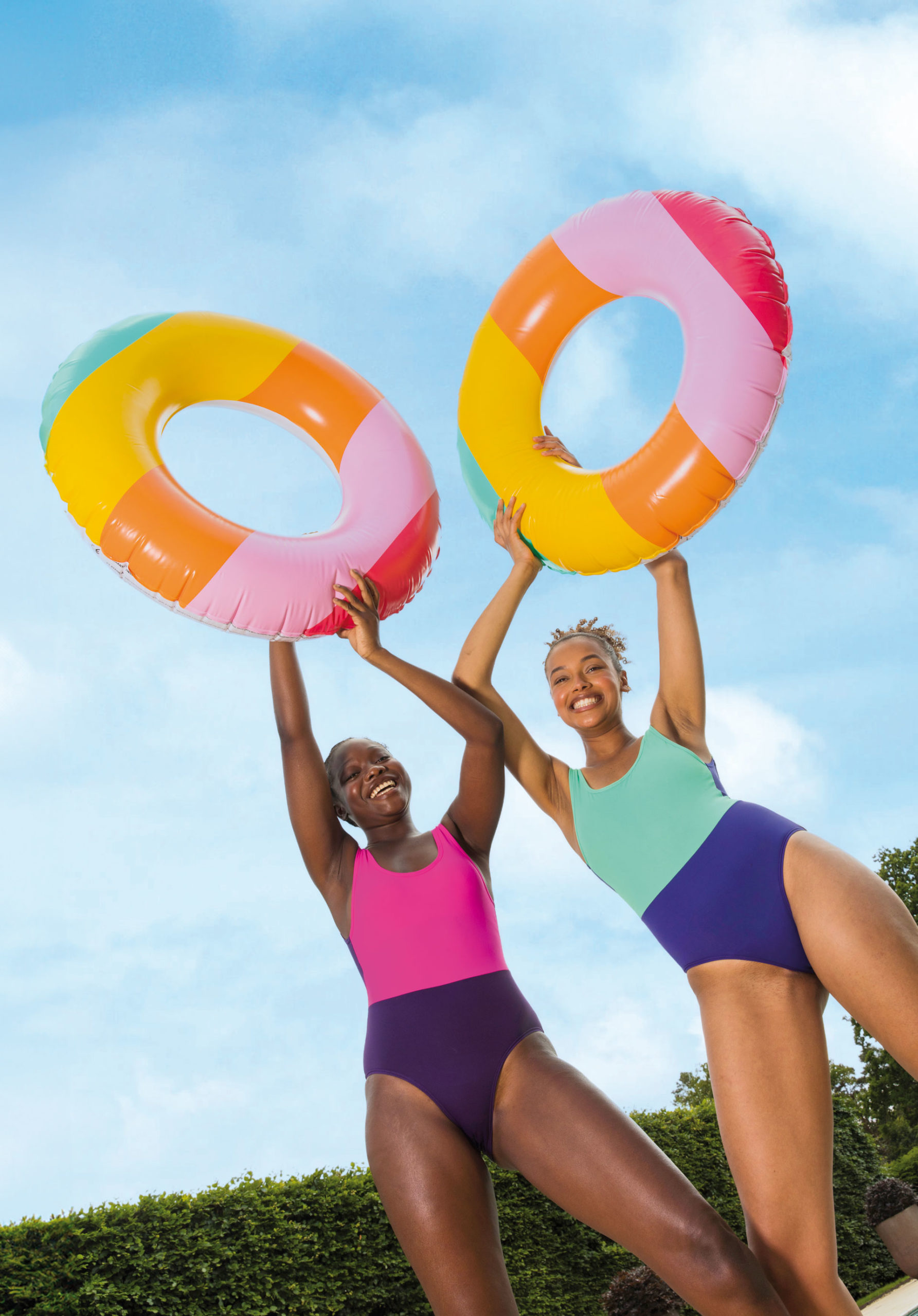 Two girls in duochrome swimsuits with inflatable rings