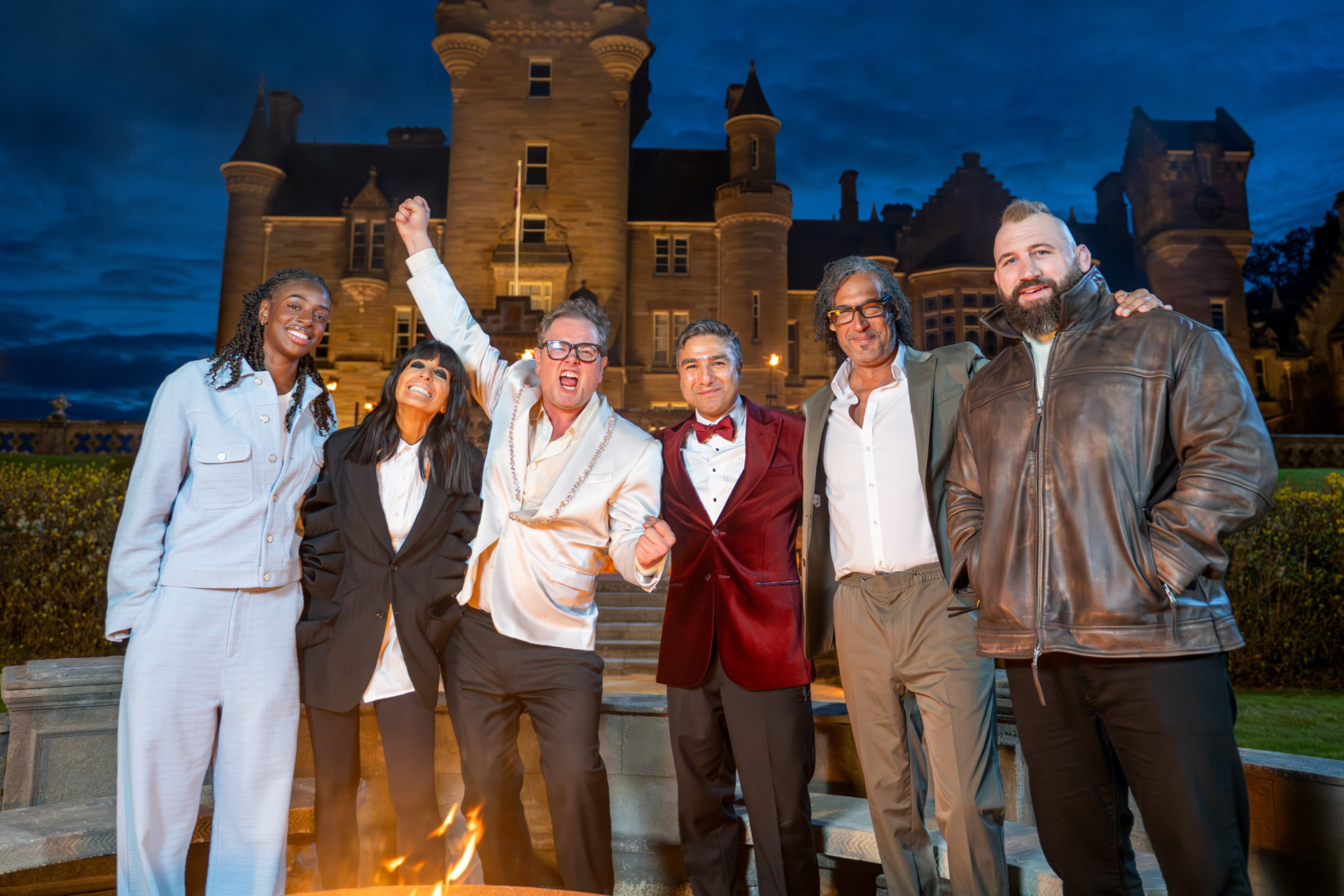 Cat Burns, Claudia Winkleman, Alan Carr, Nick Mohammed, David Olusoga & Joe Marler outside The Traitors castle