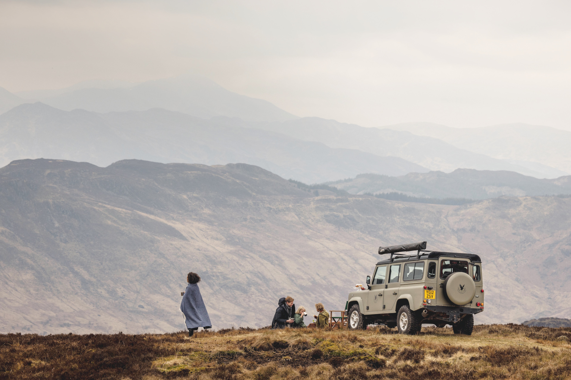 People walking in highlands next to range rover